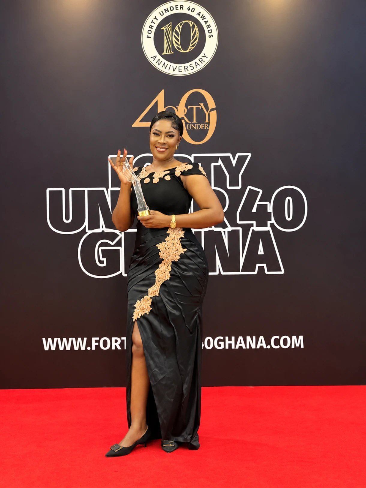 Lydia Safoa holding her award trophy on the red carpet at the Forty Under 40 Ghana Awards